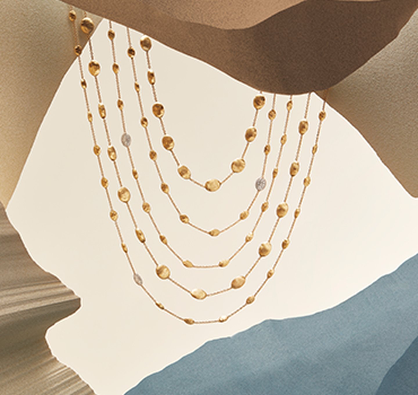 Siviglia necklaces resting on a sandy background.